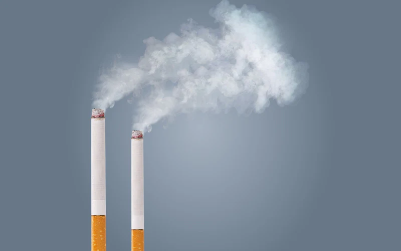 Dos cigarrillos humeantes que parecen chimeneas de fábrica